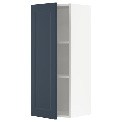 Ett METOD köksskåp med öppen blå dörr, med en modern traditionell design i mörkblått och vitt.
