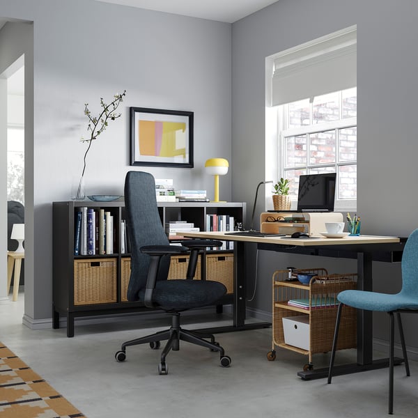 Hemmakontor med MITTZON grått skrivbord, ergonomisk stol, dator, böcker, lampa och inredning.