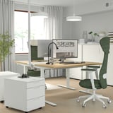 Modernt hemmakontor: MITTZON justerbart skrivbord, vitt med träskiva, grön stol, pendellampor och litet arkivskåp.