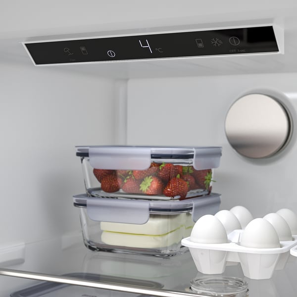 I ett modernt kylskåp förvaras jordgubbar och ost snyggt i behållare. Kylskåpets digitala display visar temperaturen vid 4°c.