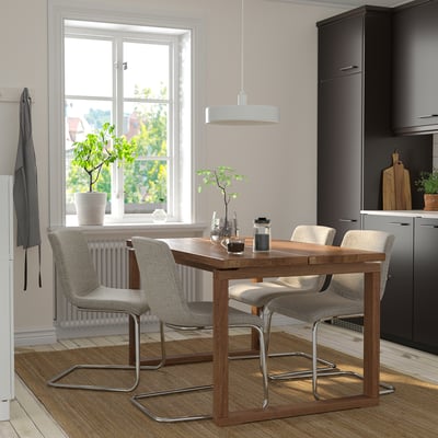 Modernt matbord i trä med kromade ben och fyra grå stolar i ett kök med grå väggar, svarta skåp och ett stort fönster.