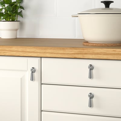 Träbänk, vita skåp, växt på grytunderlägg.