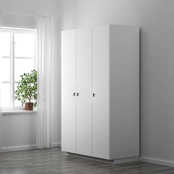 Minimalistiskt vitt skåp med eleganta, skyddande handtag nära fönstret.