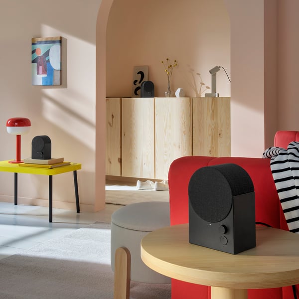 Modernt vardagsrum med livfulla färger och en snygg svart bluetooth-högtalare på ett träbord. Dekorativ och funktionell, ingår i serien NATTBAD.