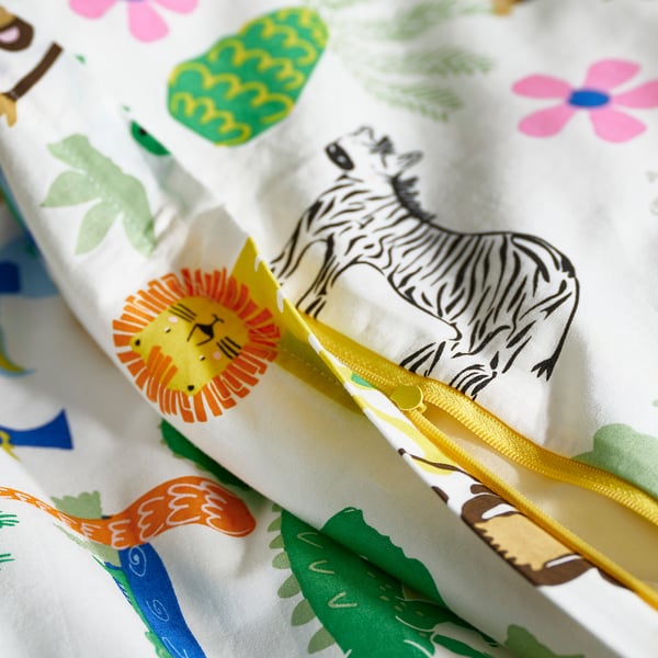 Ljusa sängkläder med zebra, lejon och gröna blad; Stängning med dragkedja.