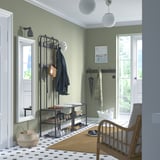 Modern entré med NIPÅSEN förvaring, bänk och korgstol. Ljusgröna väggar, svarta ramar och matta.