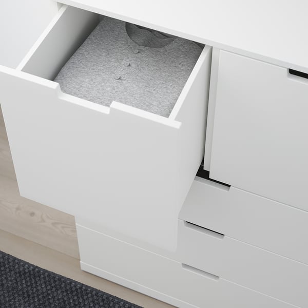En vit NORDLI byrå med en öppen låda som avslöjar en grå skjorta som visar upp dess förvaringsfunktion.