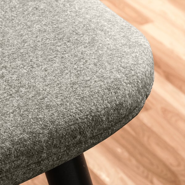 Närbild av en modern stolstol, med texturerat grått tyg spänt över en stadig ram.