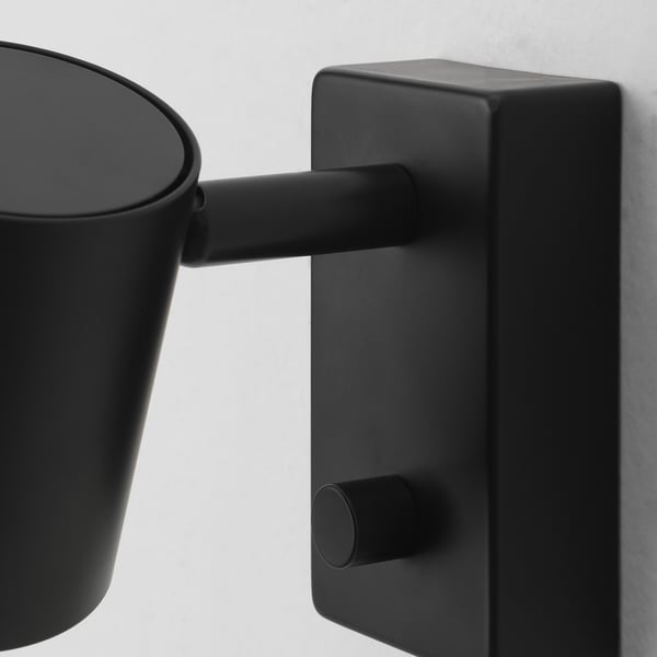 Svart justerbar vägglampa med elegant design och robust konstruktion, med en cylindrisk skärm och en metallisk finish.