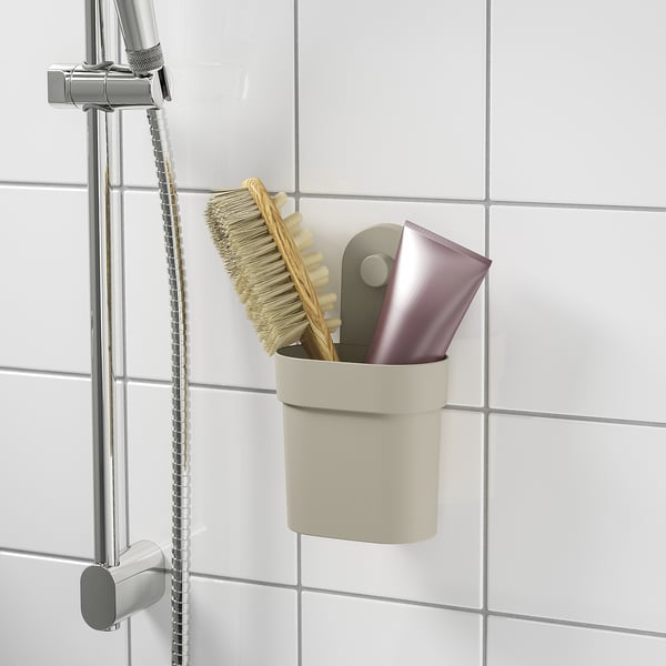 En modern badrumsorganisatör med borste och tvålhållare, fäst på kaklad vägg med sugkoppar.