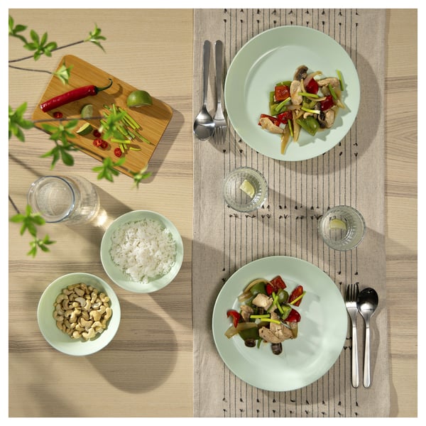 Två tallrikar wok med ris, cashewnötter och glas. Gröna glas på ett träbord.