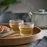 Två glas te på en träbricka, ångande, med en tekanna.