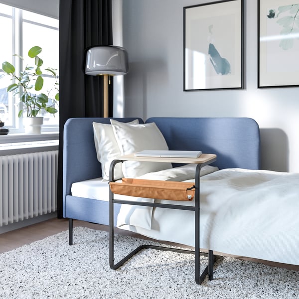 Modernt sovrum med blå soffa och justerbart olse verko laptopbord.