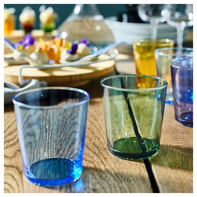 Livfulla blå och gröna glas på ett träbord, perfekt för livliga dukningar med vänner.