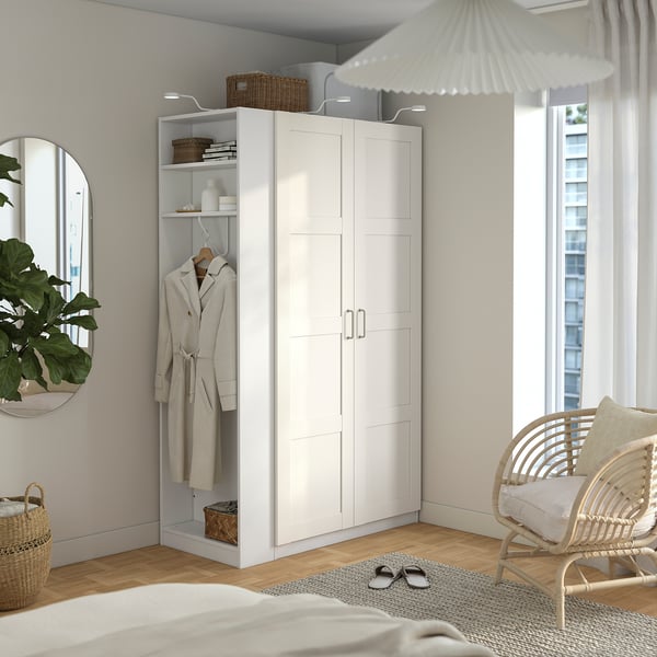 Minimalistiskt sovrum med IKEA PAX garderob, korgstol, säng, matta och stort fönster.