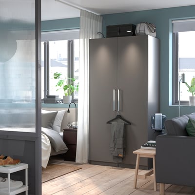 Minimalistiskt sovrum med grå PAX garderob och soffa. Elegant inredning.