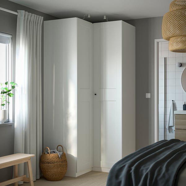 Minimalistiskt sovrum med hög vit PAX-garderob, eleganta ytor och mjuk belysning.