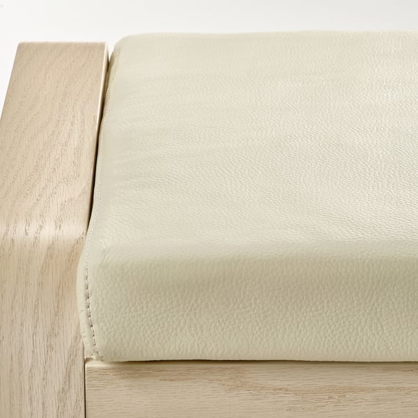 Närbild av ljus läderklädd kudde ovanpå stolsram i trä, som visar upp kvalitetsmaterial och hantverk.