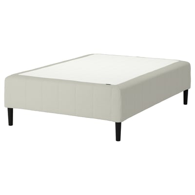 Sängbotten RÅHOLMAR i ljusbeige, med tygklädsel och ben i trä, designad för komfort och stöd.