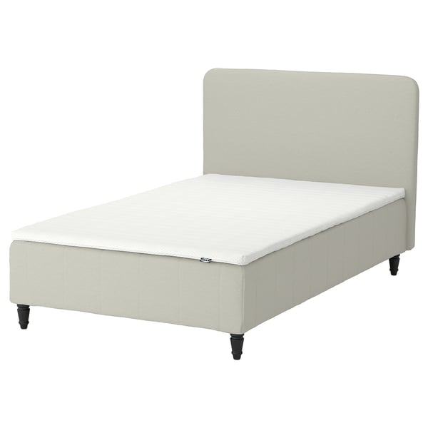 Sängen RENFJÄLLET i ljusbeige, klädd i ljust tyg, och snygga svarta ben.