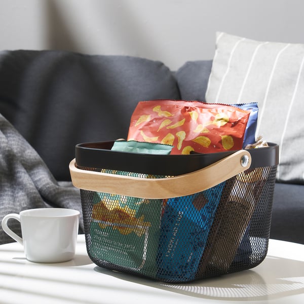 Korg på bordet rymmer snacks, med soffa och kopp i närheten.