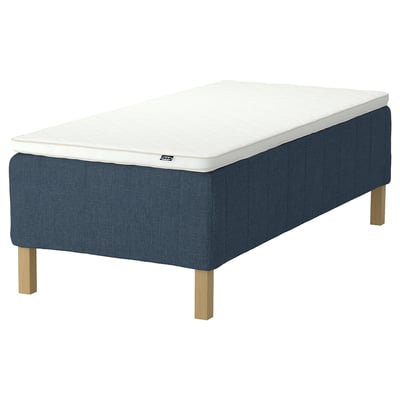 Blå klädd sängstomme med vit madrass. Ben i massivt trä. Modern, minimalistisk design.