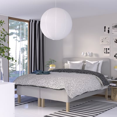 Minimalistiskt sovrum med sängen RISEHÖJDEN , pendellampa, matta och svart-vit inredning.