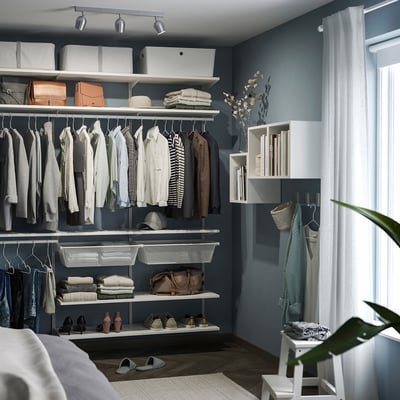 Organiserad garderob med kläder, hyllor och förvaring. Takspotlight, RÖKFRI, lyser upp prydligt arrangerade föremål. Vit, liten, modern design.