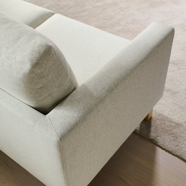 Modern soffa med slank, ljusgrå klädsel och träben, designad för komfort och enkel rengöring.