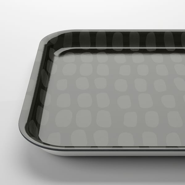 Fyrkantig bricka med vita cirkulära mönster på grå bakgrund, glänsande yta.