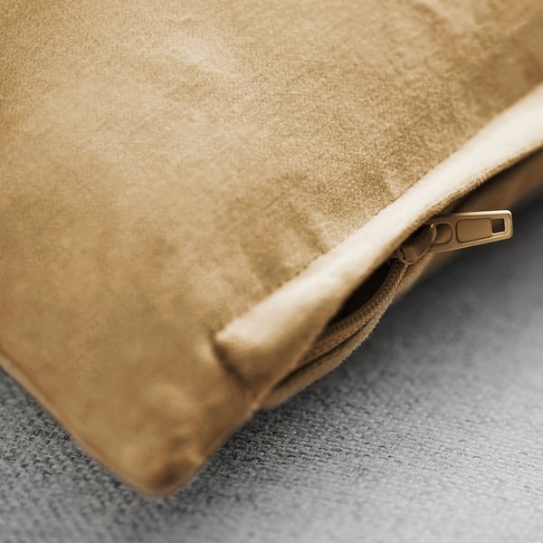 Närbild på lyxigt beige kuddfodral i sammet med dragkedja som antyder högkvalitativt tyg och hantverk.