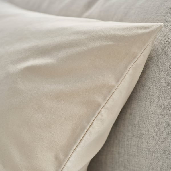 Närbild av lyxigt, slätt beige kuddfodral i sammet på en säng, som visar upp mjuk struktur och elegant finish.
