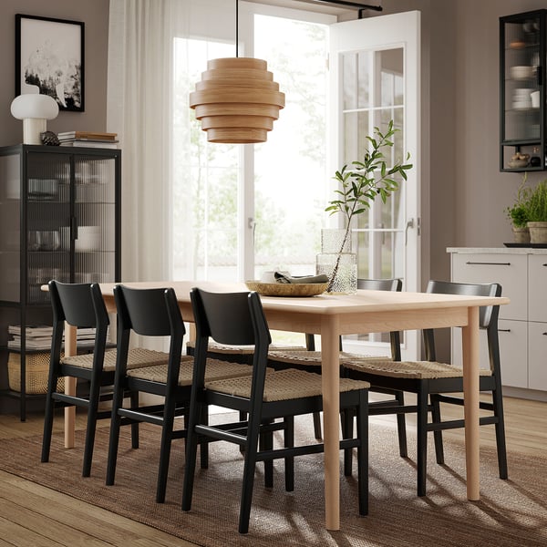 Modern matplats med SKANSNÄS bord och svarta stolar, trägolv, naturlig inredning.