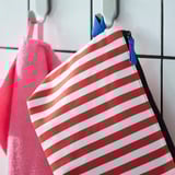 En randig necessär hängde på en krok och visade sina många fack för organisation.