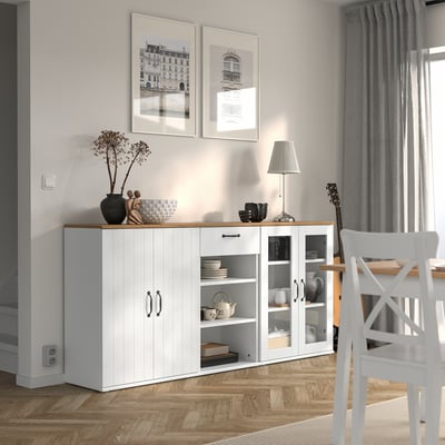 Modern vit skänk i matplats med inredning, gitarr, växt och inramade bilder.