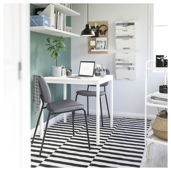 Modernt kontor med lampan SKURUP, stilrent skrivbord, grå stol och randig matta.