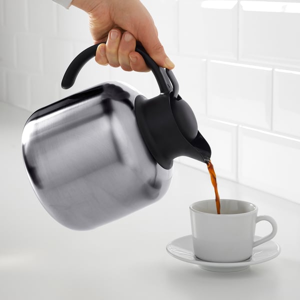 Häller kaffe från isolerad kanna i koppen.