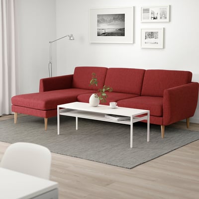 Röd SMEDSTORP sektionssoffa, modern retrostil, med högelastiskt skum. Vitt soffbord, grå matta, svartvita foton.