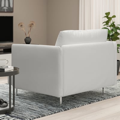 Modernt minimalistiskt vardagsrum: stor vit SÖDERHAMN fåtölj på matta, bredvid litet bord med kopp, böcker och vas, nära tv och växt.