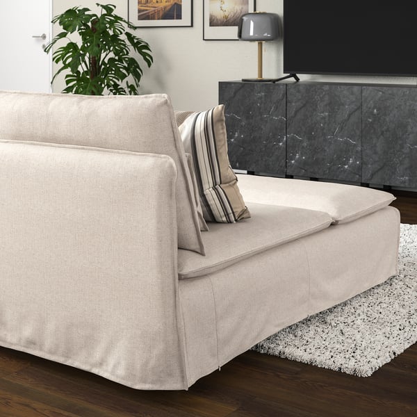 SÖDERHAMN beige schäslong på matta, bredvid växt & tv-bänk. Mjuk, elegant och inbjudande.