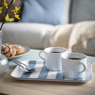 Bricka SOLDATFISK, vit/blårandig, rektangulär, rymmer två kaffekoppar och en tallrik med bakverk. Passar bra på ett bord, ljus träyta.