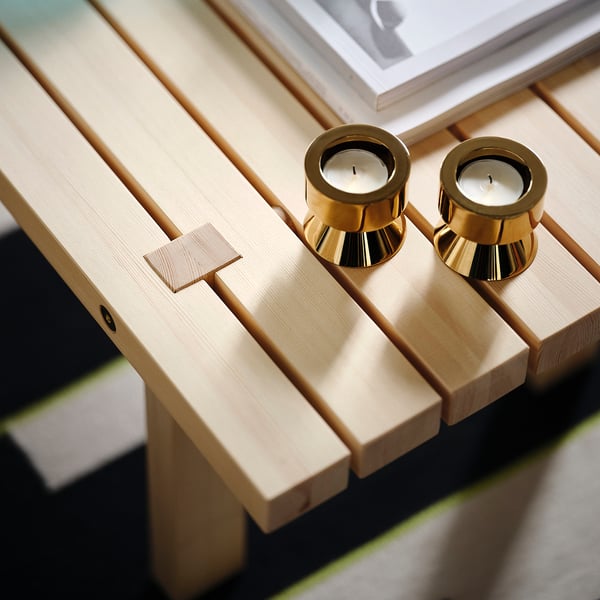 En minimalistisk träbänk med gyllene ljusstakar på. Den är tillverkad av ljust trä, eleganta designdetaljer och högkvalitativ finish.