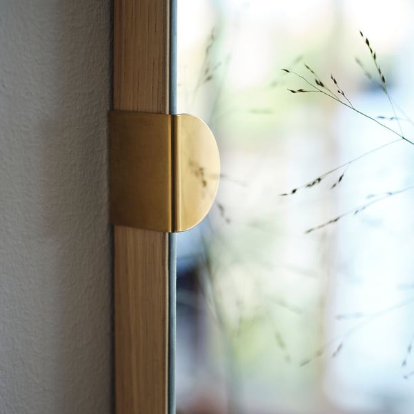 Fyrkantig spegel med guldbeslag, reflekterande yta i ekram. Designad för elegans och funktionalitet.