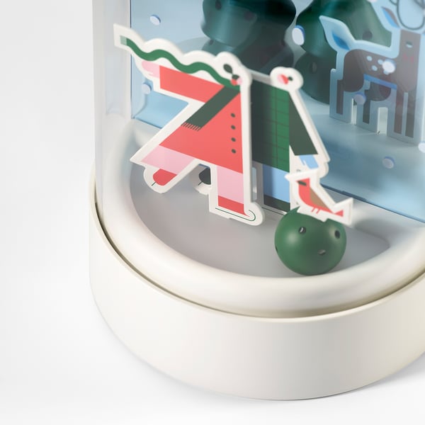 Dekorativt snöscenljus med färgrik spis, klar jordglob, mjukt ljus, sitter på vit bas.