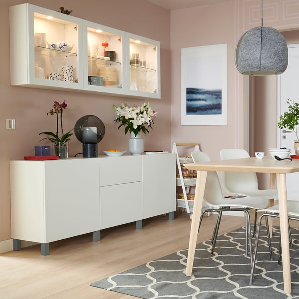 Modern matsal med förvaring bestå, glasdörrar, mörkgrå ben, träbord, vita stolar och matta.