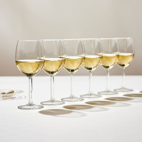 Sex vinglas, vart och ett fyllt med vitt vin, står prydligt uppradade på en vit duk och förstärker vinets aromer och smaker.
