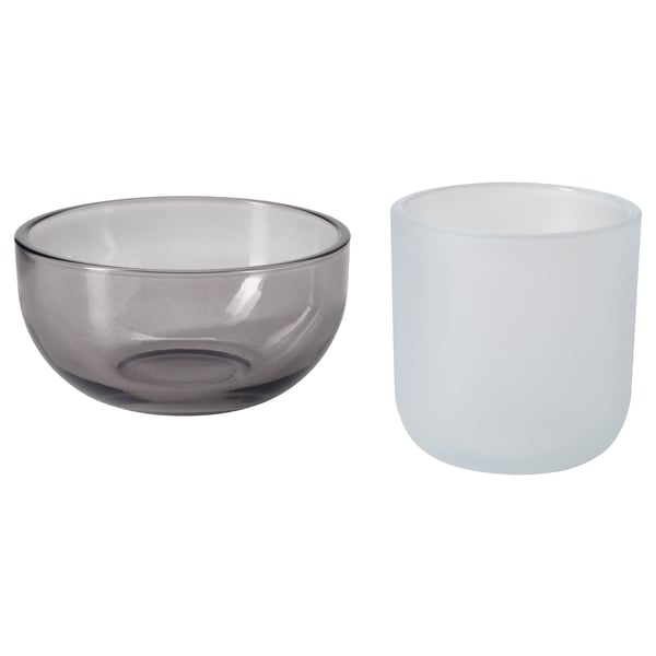 Set med 2 TALLTITA värmeljushållare i glas, en grå, en vit, rund form, enkel design.