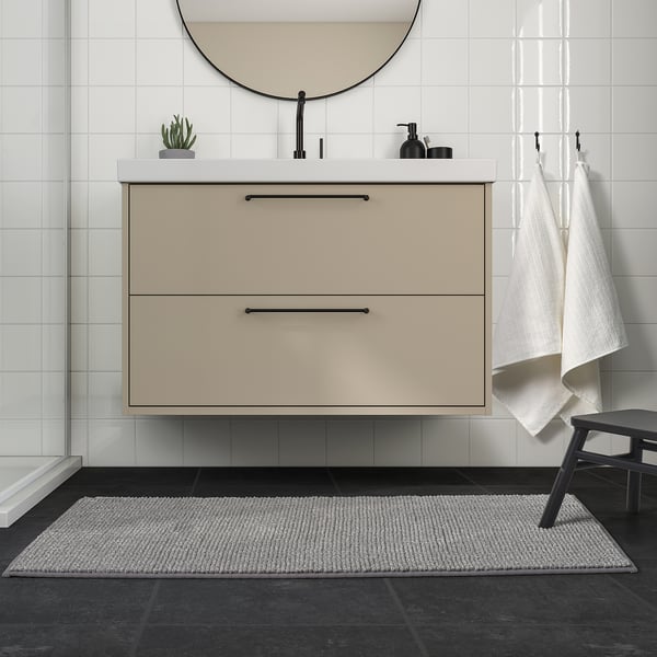 Modernt badrum med beige fåfänga, svarta armaturer och TOFTBO grå badrumsmatta, rektangulär, mjuk, passar under fåfänga.