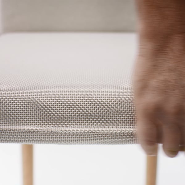 Närbild av en modern stol med vävt, ljust tyg, som visar högkvalitativ design och komfort.