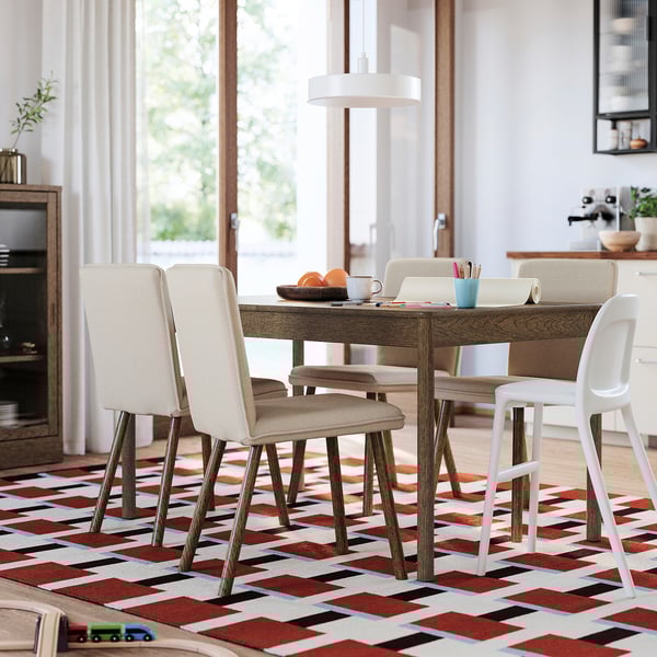 Modern matplats med utdragbart bord, stoppade stolar och matta. Naturligt ljus fyller det ljusa rummet.